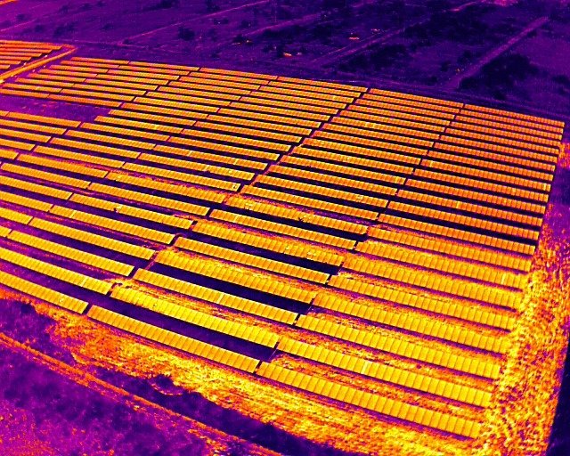 Termograma aéreo de usina fotovoltaica de solo, com pontos de aquecimento marcados em vários módulos